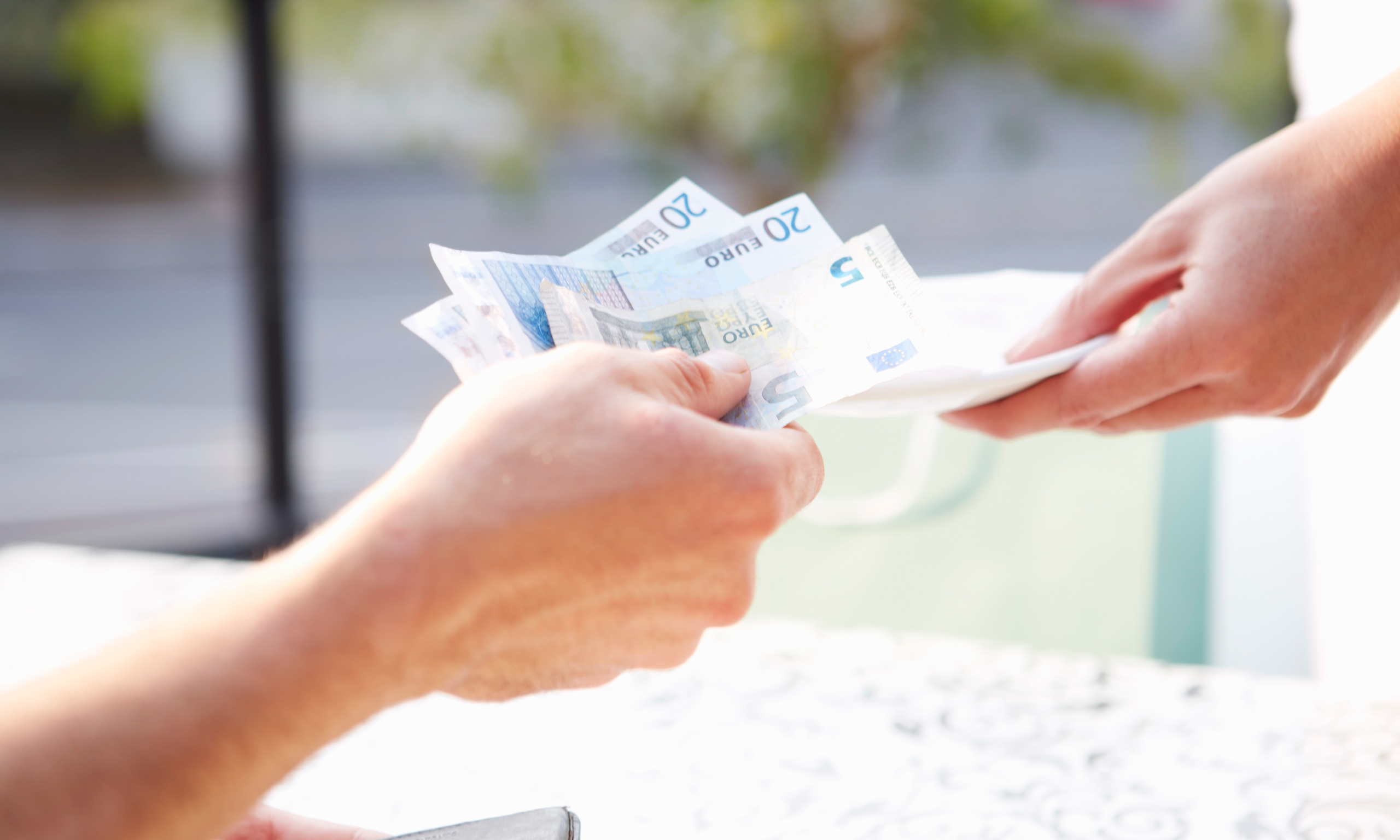 A customer hands over euro bills to make a payment after a repair at Service Centre. The transaction takes place at a service desk with a soft background blur.