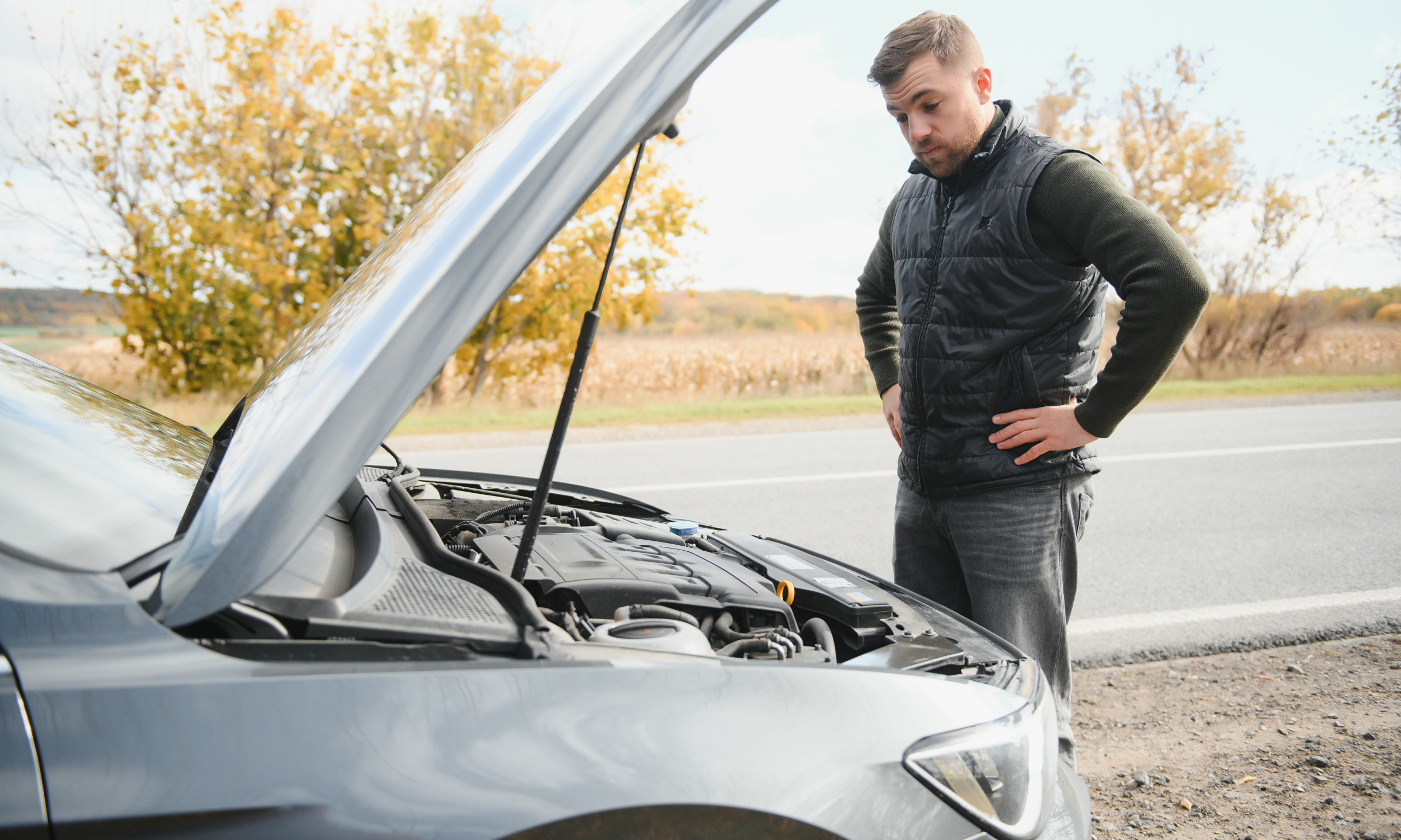 A concerned driver inspects a car engine, possibly due to a cambelt issue.