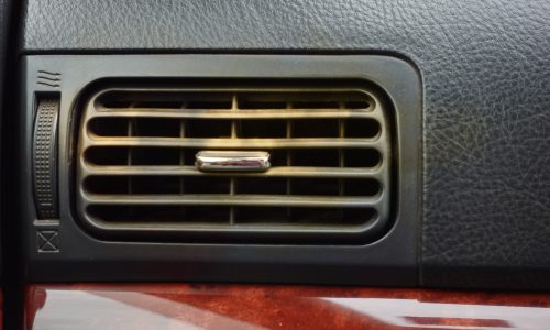 A close-up of a dusty car air con vent, indicating a potential source of air con smell.
