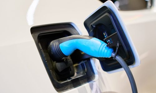 Close-up of electric car charging cable – modern car care tips for EV battery maintenance.