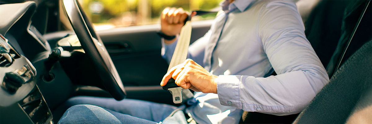 a man sitting in a car fastening his seatbelts