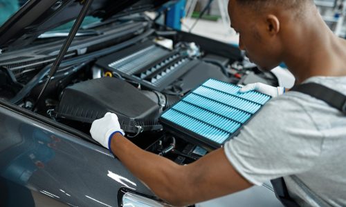 Mechanic replacing car air filter under the hood – essential car care tips for better engine performance.