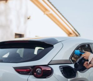 A young woman is plugging in her electric car to charge the vehicle.