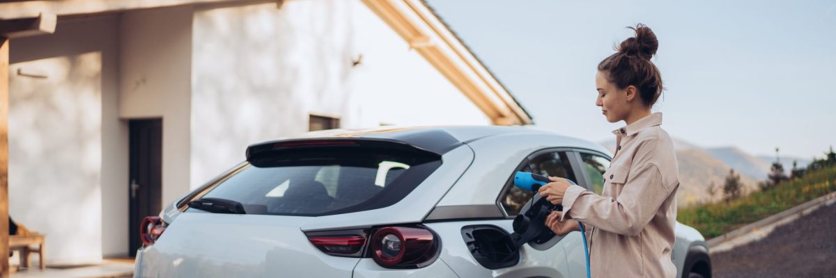 A young woman is plugging in her electric car to charge the vehicle.