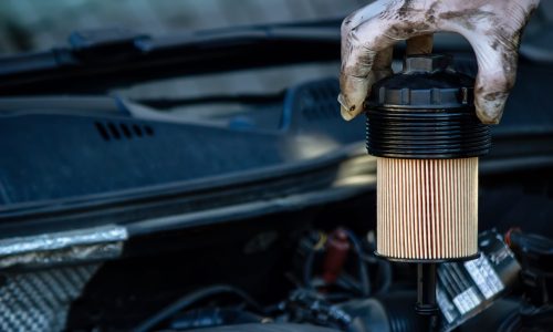 Mechanic replacing used oil filter during routine car service.